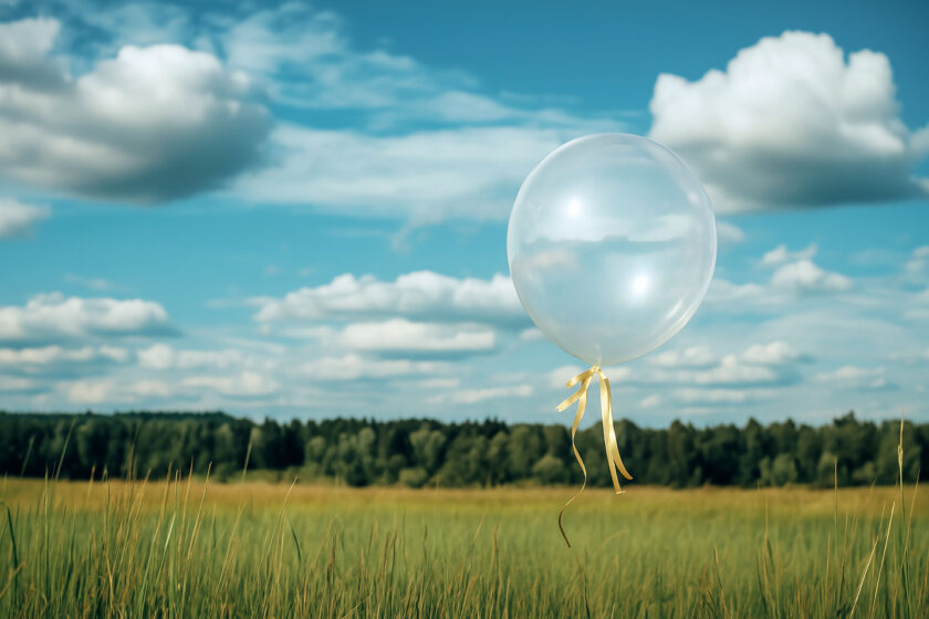 A single balloon floating in the sky over peaceful countryside, symbolising remembrance, love, and the beauty of a heartfelt memorial service.